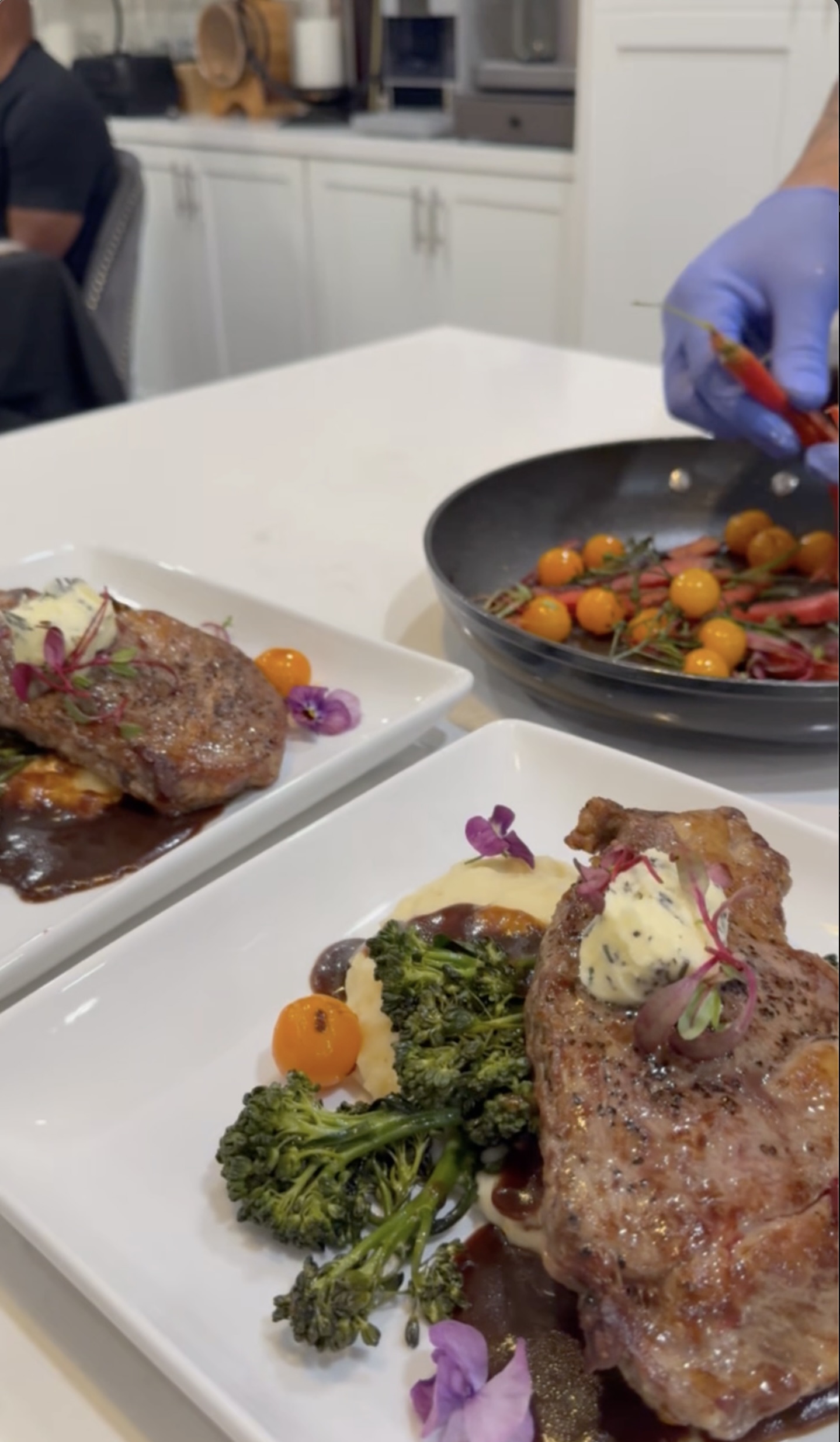 Chef G preparing gourmet steak plates with herb butter and edible flowers for an intimate romantic dinner